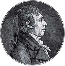 A man with long, braided hair wearing a high-collared, white shirt and dark jacket