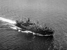 Aerial view of cargo ship at sea, with numerous large cranes and other loading equipment visible on the decks fore and aft