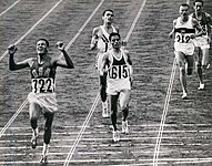 Zieleinlauf im 10.000-Meter-Finale 1964: Mit der 722 der Olympiasieger Billy Mills aus den USA, mit der 615 Mohammed Gammoudi aus Tunesien mit Silber. Direkt hinter Gammoudi Ron Clarke auf Platz 3