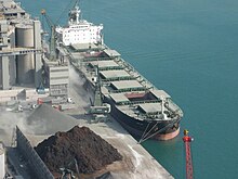 A relatively large bulk carrier loading a grey aggregate