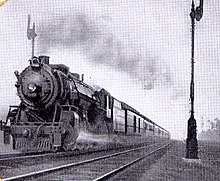 An old black and white photo of a steam locomotive pulling a fast passenger train