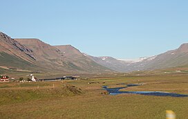 Photo showing the town of Hof in the distance and the Hofsá river running on the flat land in Unadalur