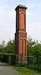 A chimney-like brick structure in two stages with some brick decoration and a corbelled top