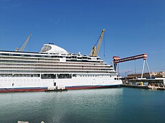 Nave “Seven Seas Grandeur” della compagnia Regent Seven Seas, in allestimento allo stabilimento Fincantieri (2022). Ha 55.000 tonnellate di stazza lorda, una lunghezza di 223 metri e può ospitare 750 passeggeri. Sullo sfondo, la gru a cavalletto del cantiere.