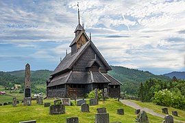 Foto einer Stabkirche mit Grabsteinen im Vordergrund