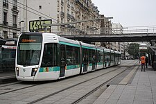 Zug der Linie T3a in der Endstation Porte de Vincennes unter der Brücke der Petite Ceinture, im Hintergrund die Wende- und Abstellanlage