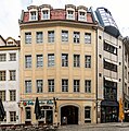 Wohn- und Handelshaus in geschlossener Bebauung, mit Hofbauten und Rückgebäude an der Kleinen Fleischergasse sowie Erker des Vorgängerbaus (Anschrift: Hainstraße 1 und Markt 8 sowie Kleine Fleischergasse 2)