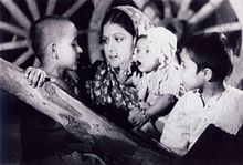 A screenshot from the film Aurat showing an Indian woman with three children.