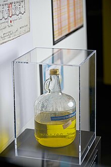 A big glass jug filled with dirty yellow water in a display case