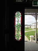 Stained glass window with verandah fretwork and Corinthian capital visible