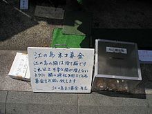 A sign with Japanese characters next to a donation box with coins inside