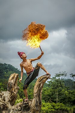 Seorang penari api sedang menyemburkan api dengan bahan bakar dari mulutnya