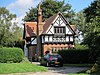 A house in Tudor Revival style with a brick lower storeys and a gabled timber-framed upper storey