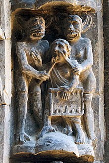 Sculpture of two horned grinning figures applying instruments to the face and tongue of a man holding a game board.