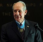 Captain Hudner addresses a crowd wearing his Medal of Honor