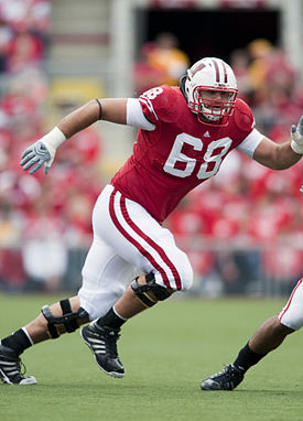 Man in red football jersey with white number 68 emblazoned on it running