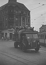 Kreuzung Karlshorster Straße Ecke Türrschmidtstraße während der 3. Weltfestspiele 1951. Der Lkw überfährt gerade das aus der Türrschmidtstraße kommende Gleis, am rechten Bildrand biegt ein Mitteleinstiegswagen von der Marktstraße in die Karlshorster Straße ein. Das Schmalspurgleis im Vordergrund gehört zur Trümmerbahn Schloßplatz – Friedrichsfelde.