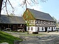 Wohnstallhaus, Mühlenanbau mit erhaltener Technik und Mühlrad, Mühlteich und umgebendem Baumbestand