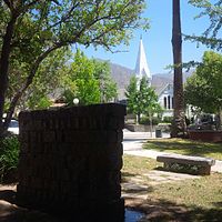 Sierra Madre Memorial Park at Sierra Madre Blvd and Hermosa looking North. From foreground to background: Weeping Wall Veterans Memorial, Sierra Madre Veterans Time Capsule bench, 1905 World War I Cannon, Sierra Madre Boulevard, The Old North Church and the San Gabriel Mountains