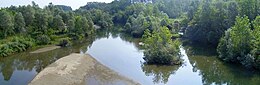 Photo shows a small river bordered by many trees.