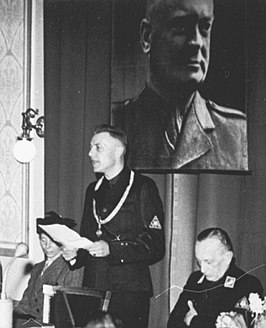 Tammens spreekt tijdens zijn installatie in 1943. Links zijn vrouw, rechts Staargaard (Commissaris der Provincie), boven het portret van Mussert