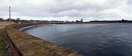 A large reservoir with a low wall running around the edge