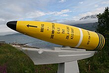 A translation of the Norwegian text on the plaque below the shell: "This shell was fired from the German battleship "Tirpitz" while at anchor at Håkøybotn during an airstrike 29 October 1944. The airstrike consisted of 39 Lancaster bomber planes from RAF´s 617th and 9th squadron. These planes came from England, arriving above Lyngfjellene (nearby mountains) and Sjursnes (this shell is displayed at Sjursnes in Ullsfjord) heading towards Tromsø. The shell struck down in a bog about 800 meter from here (Sjursnes) without detonating. It was recovered during excavation work in the autumn of 1967."