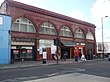 A red-bricked building with "CALEDONIAN RD." in gold letters and a blue sign reading "CALEDONIAN ROAD STATION" in white letters below