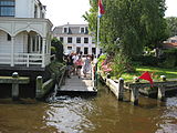 Zicht op Amstelzijde waar de brug lag met links het brugwachtershuisje, in het midden het Jan Coevertveer.