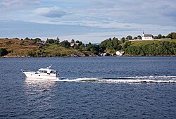 Bilde av lysbåt seilende midt i bilde, på stille hav. Sol og blå himmel.