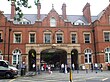 A red-bricked building with a sign reading "MARYLEBONE STATION" in beige letters, a blue roof, and a crowd of people in front