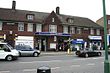 A red-bricked building with a rectangular, dark blue sign reading "PRESTON ROAD STATION" in white letters all under a clear, white sky