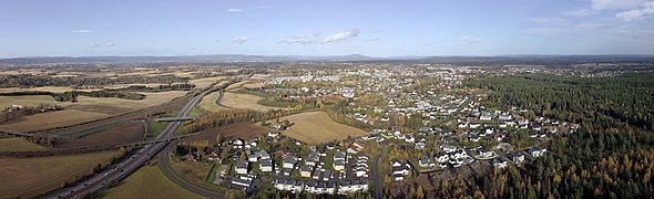 Foto einer von Wald und Feldern umgebenen Stadt in flacher Landschaft mit einer breiteren Straße links im Bild