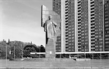 Steinerne Statue von Lenin vor einem Hochhaus, mit Schärpe, beschriftet mit den Worten „Keine Gewalt“.