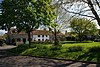 Grassy area with trees in the foreground and a terrace of stone houses, one white fronted, in the background