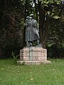 Kriegerdenkmal: Bronzegruppe mit Steinsockel, Treppenanlagen, Bruchsteinmäuerchen, Rasenfläche, zwei Blutbuchen, Hecke, Ahorn