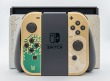 Das Foto zeigt im Vordergrund die Joy-Cons im Tears of the Kingdom-Stil mit Halterung und dahinter die Konsole, gedockt in der Docking Station