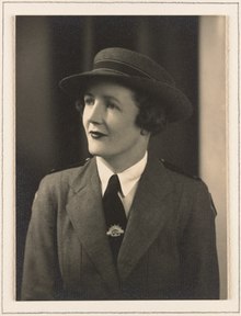 Portrait of a woman, bust, facing to her right, wearing military uniform and hat.