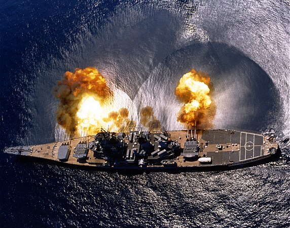 USS Iowa (BB-61) fires a full broadside of her nine 16″/50 and six 5″/38 guns during a target exercise near Vieques Island, Puerto Rico (21°N 65°W﻿ / ﻿21°N 65°W). Note concussion effects on the water surface, and 16-inch gun barrels in varying degrees of recoil.