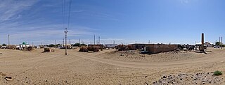 A panorama from the entrance to the village of Erbent (Yerbent). On the right side of the photo a group of tourists standing next to the Basmachi Revolt monument can be seen.