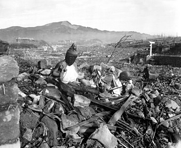 Atom bombası saldırısı sonrasında Nagasaki'nin Urakami bölgesinde yer alan Sakamoto mahallesinin görünümü. 24 Eylül 1945 tarihinde Strategic Bombing Survey'nin incelemesi sırasında Deniz Piyade Onbaşısı Lynn P. Walker, Jr. tarafından çekildi. Önde Kannon Bosatsu ve Jizō Bosatsu heykelleri, sağ tarafında Sannō Jinja (ground zero'nun 800 metre güneydoğusu)'nın "Ipponbashira Torii" ("Tek Sutünlü Torii")'si görülmektedir. İleride solda Chinzei Gakuin Ortaokulu Takenokubo Kampüsü (ground zero'nun 500 metre güneybatısı, günümüzde Kassui Lisesi), ortada Shiroyama Millet Okulu (ground zero'nun 500 metre batısı, günümüzde Shiroyama İlkokulu), Arkasında görülen yükselti ise Iwaya Dağı'dır. (Üreten: Lynn P. Walker, Jr.)