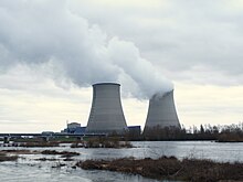 Nuclear power plant in Cattenom, France four large cooling towers expelling white water vapour against a blue sky