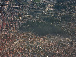 Luchtfoto met de beboste heuvel met daarop de kasteelruïne