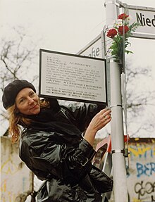 Eine Frau hängt ein weiteres Straßenschild an eine Kreuzung