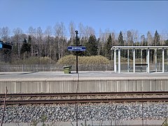 Stationsnaambord en abri op het perron.