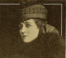 A woman with fair skin, wearing a hat