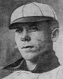 A man in a light baseball uniform and cap