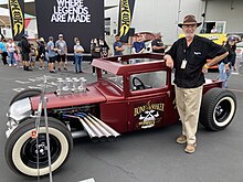 Larry Woods, Hot Wheels designer, posing next to a vintage car