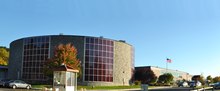 A high school building, with a round auditorium in the foreground and a two-story rectangular brick building in the background.