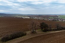 The image depicts an agricultural field, with the village of Nedasovce appearing behind it.